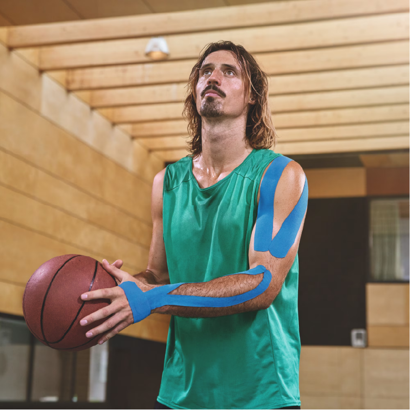 Leukotape K bleu porté sur l'épaule et l'avant bras d'un joueur de basket